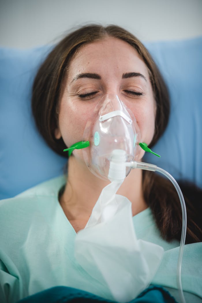 services-04 Caucasian woman in hospital bed wearing oxygen mask for medical treatment and recovery.